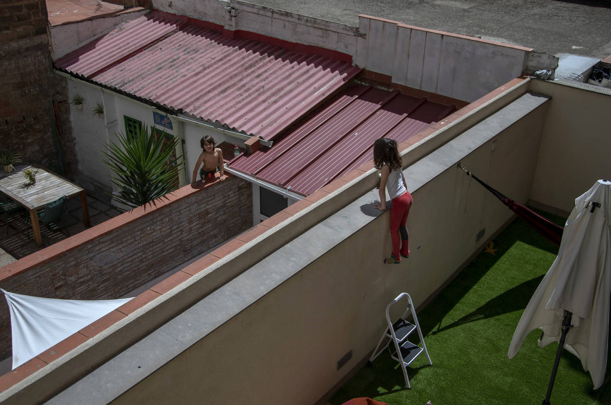 Gala, 7, speaks with her friend and classmate Oliver, 6, as they jump on the wall on their cour ...