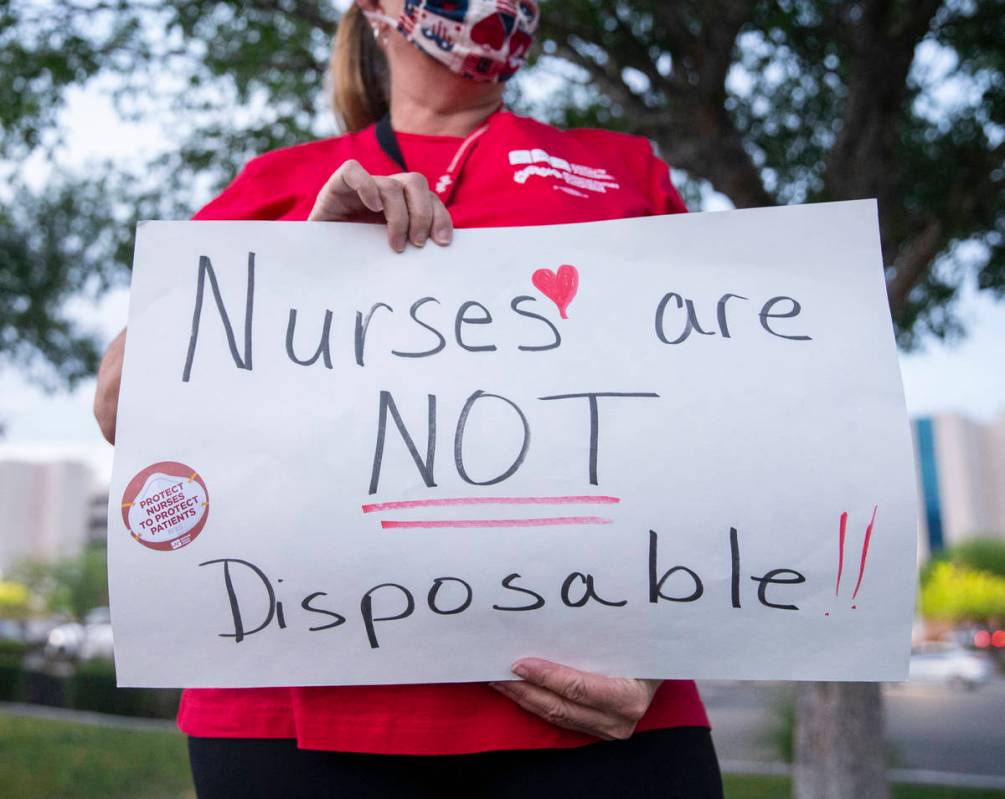 Recovery room nurse Lauren Elfman holds a sign advocating for better protection, testing and be ...