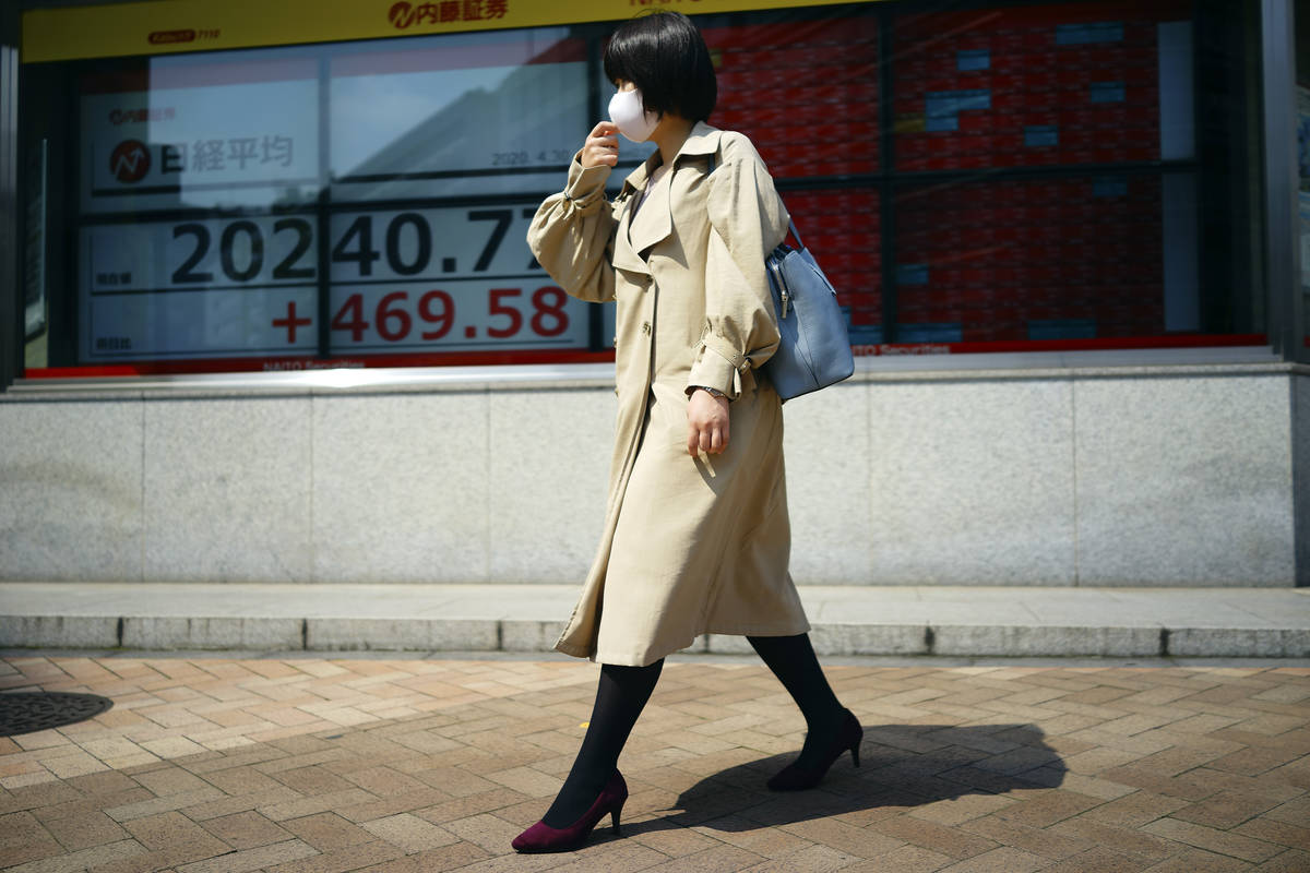 A woman walks past an electronic stock board showing Japan's Nikkei 225 index at a securities f ...