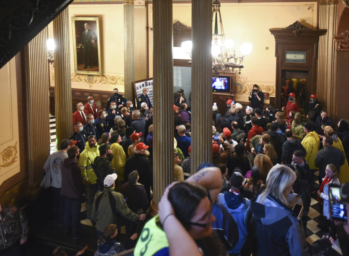 People protest outside the entrance of the Michigan House of Representatives in Lansing, Mich. ...