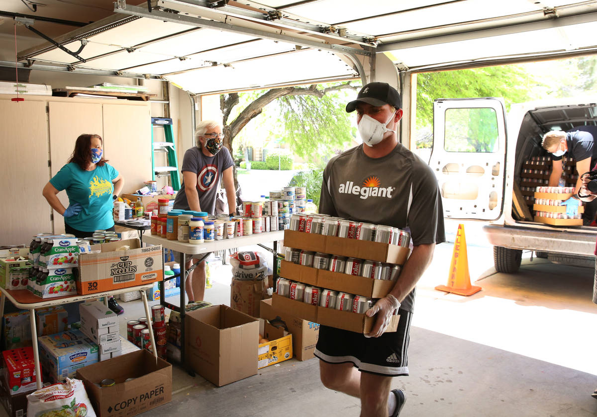 Jeana Taylor, left, founder of Vegas Community Pantry, and her husband Scott watch as Andrew Po ...