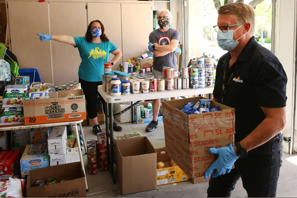 Jeana Taylor, left, founder of Vegas Community Pantry, and her husband Scott watch as Darren Ra ...