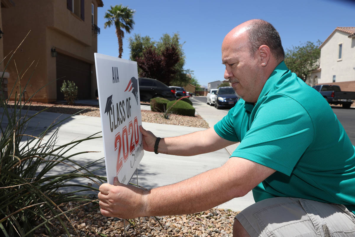 Steve Rosenthal installs a yard sign to the home of a Liberty High School senior in Henderson, ...