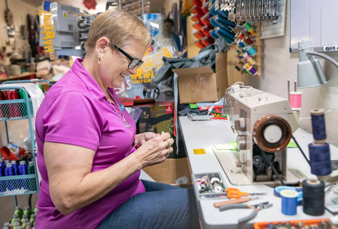 Michele Walker, owner of Imaginations Unlimited, sews a cloth face covering, in her embroidery ...