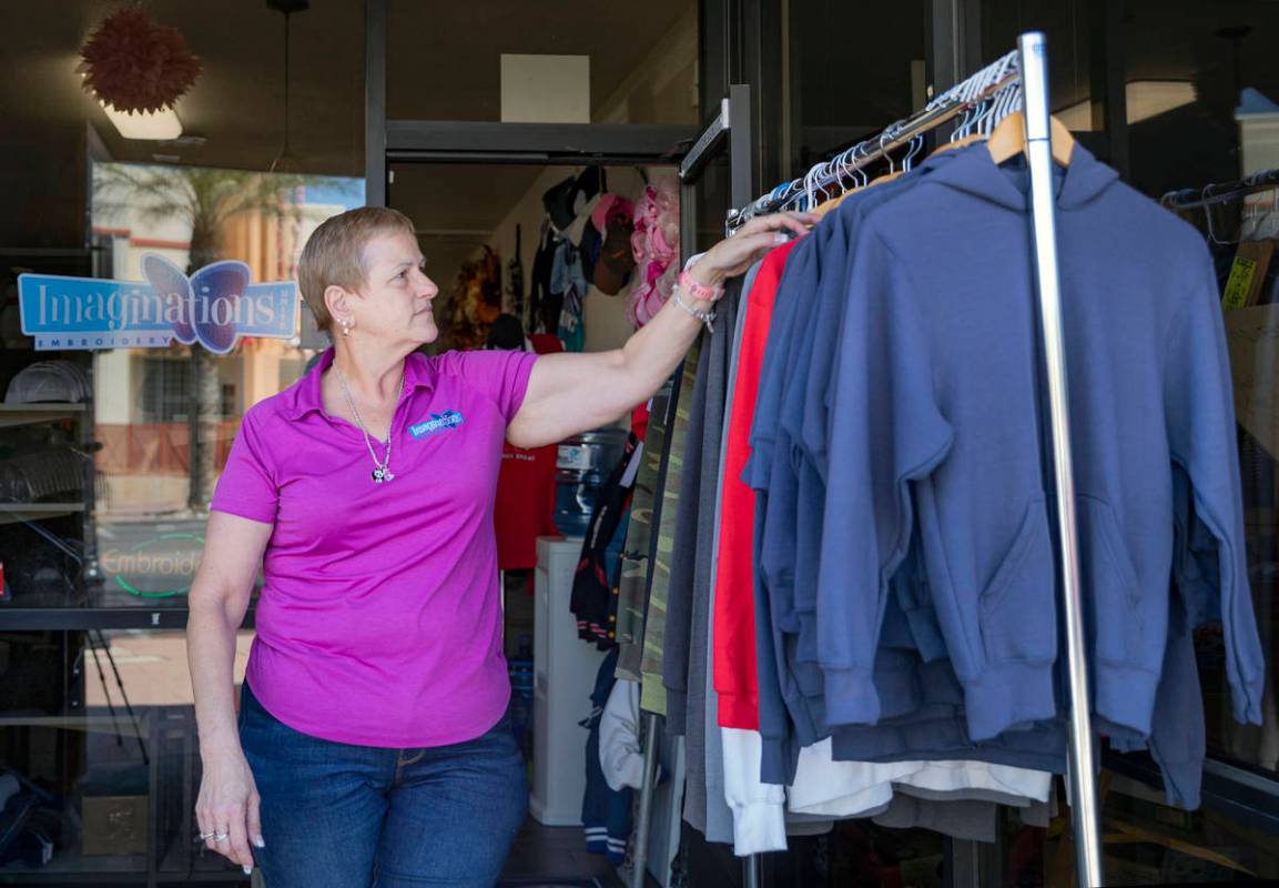 Michele Walker, owner of Imaginations Unlimited, organizes clothes out on the sidewalk to visua ...