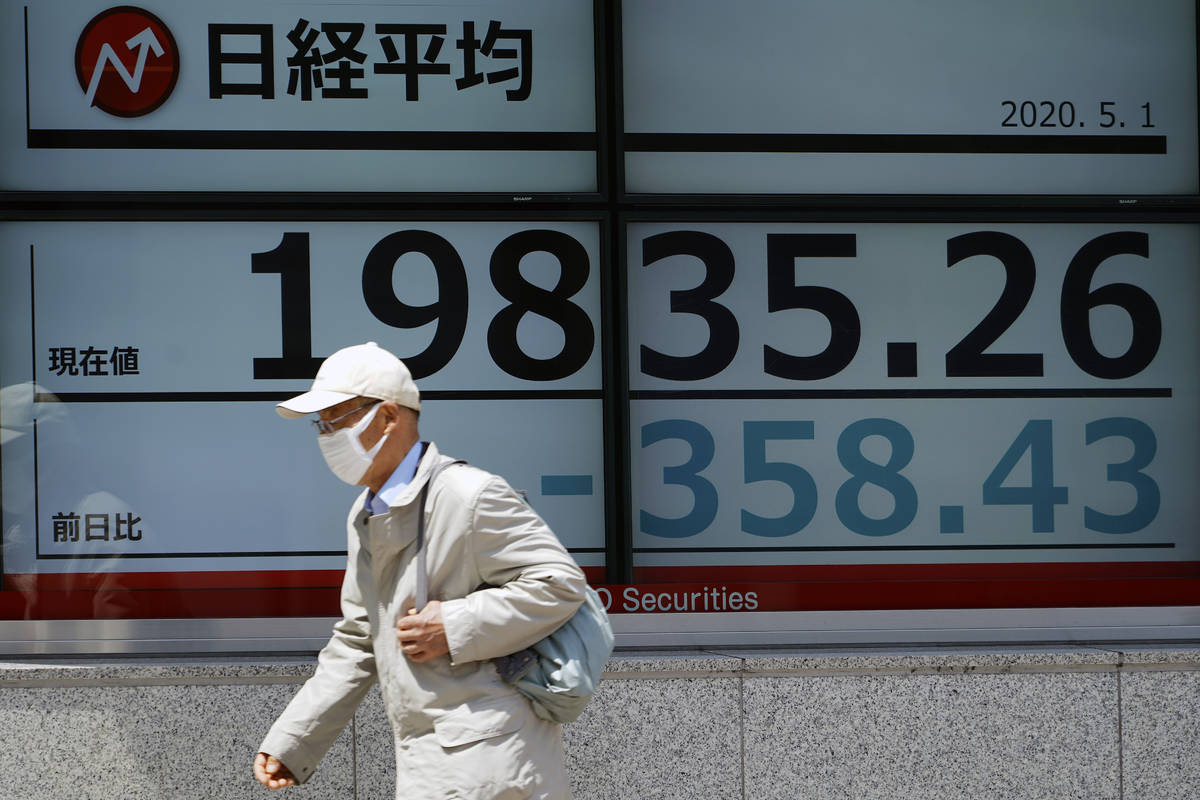 A man walks past an electronic stock board showing Japan's Nikkei 225 index at a securities fir ...