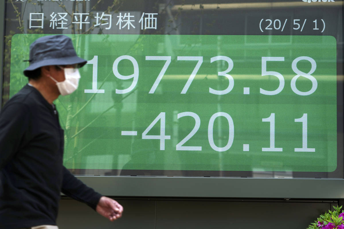 A man walks past an electronic stock board showing Japan's Nikkei 225 index at a securities fir ...