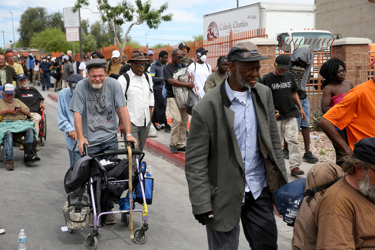 People, including Earl Betts, left, line up for a meal at Catholic Charities on Foremaster Lane ...