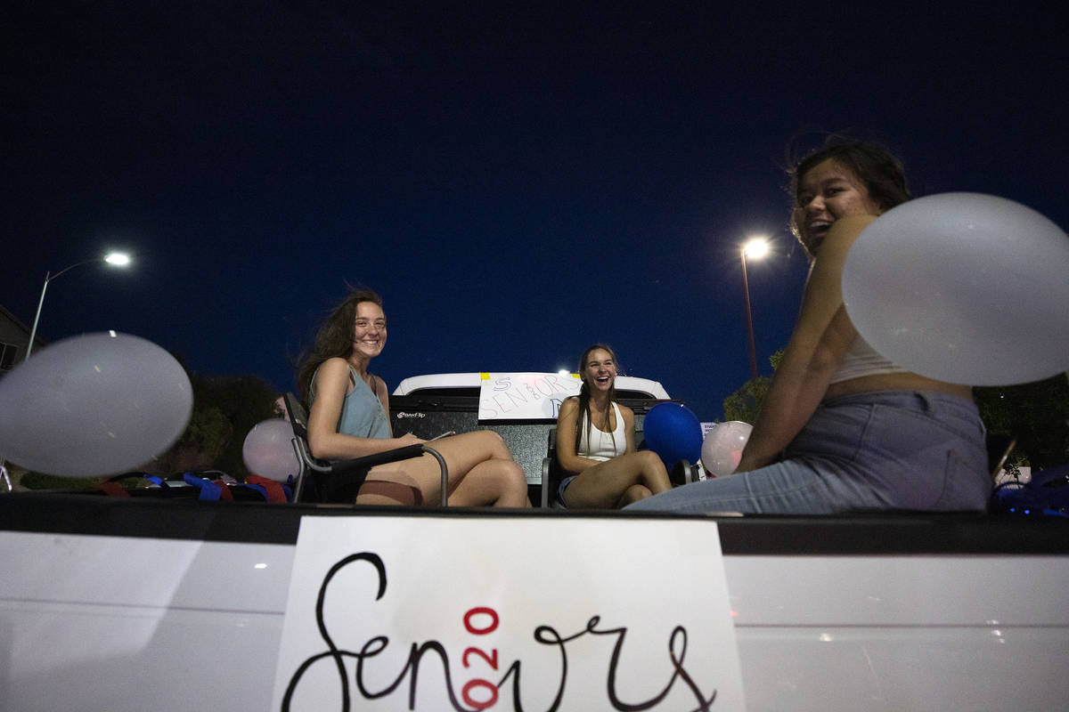 Three seniors ride in the back of a pick up truck along with much of the rest of their class of ...