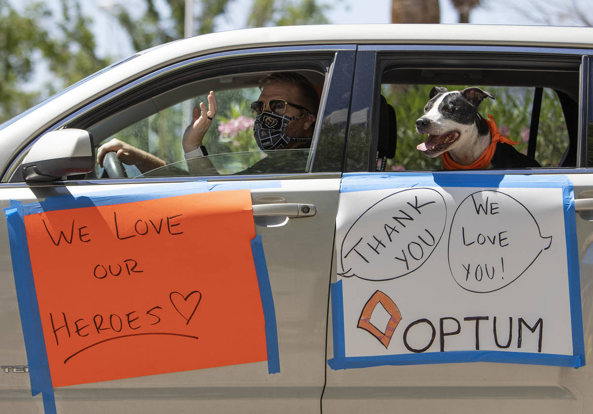 A masked driver thanks Southwest Medical staff for their work during a car parade at OptumCare' ...