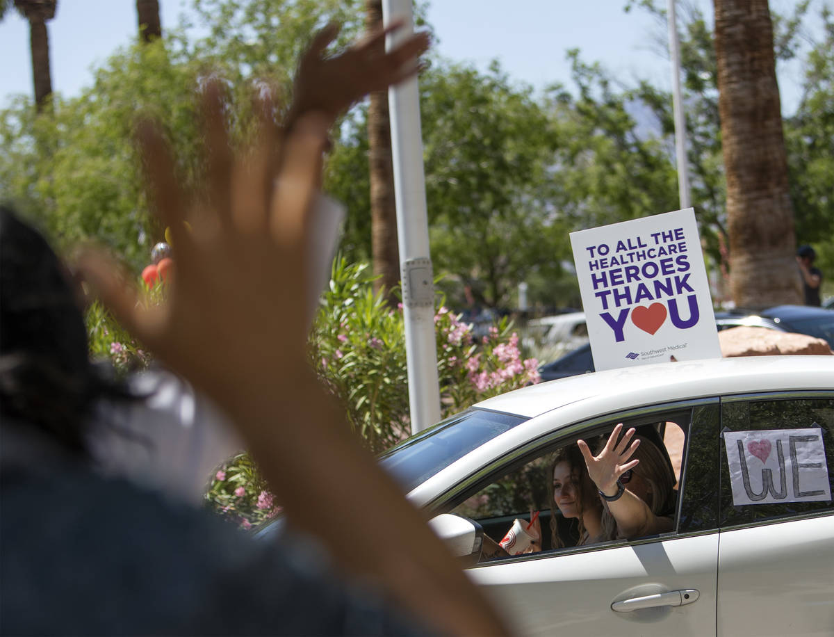 Vehicles drive through to thank Southwest Medical physicians and nurses as the staff waves back ...
