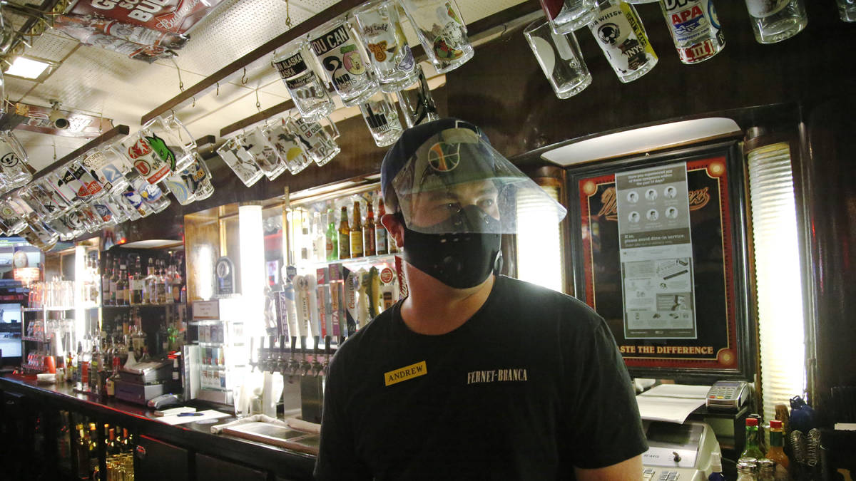 Cheers to You bartender Andrew Lohry wears a mask and face shield behind the bar Friday, May 1, ...