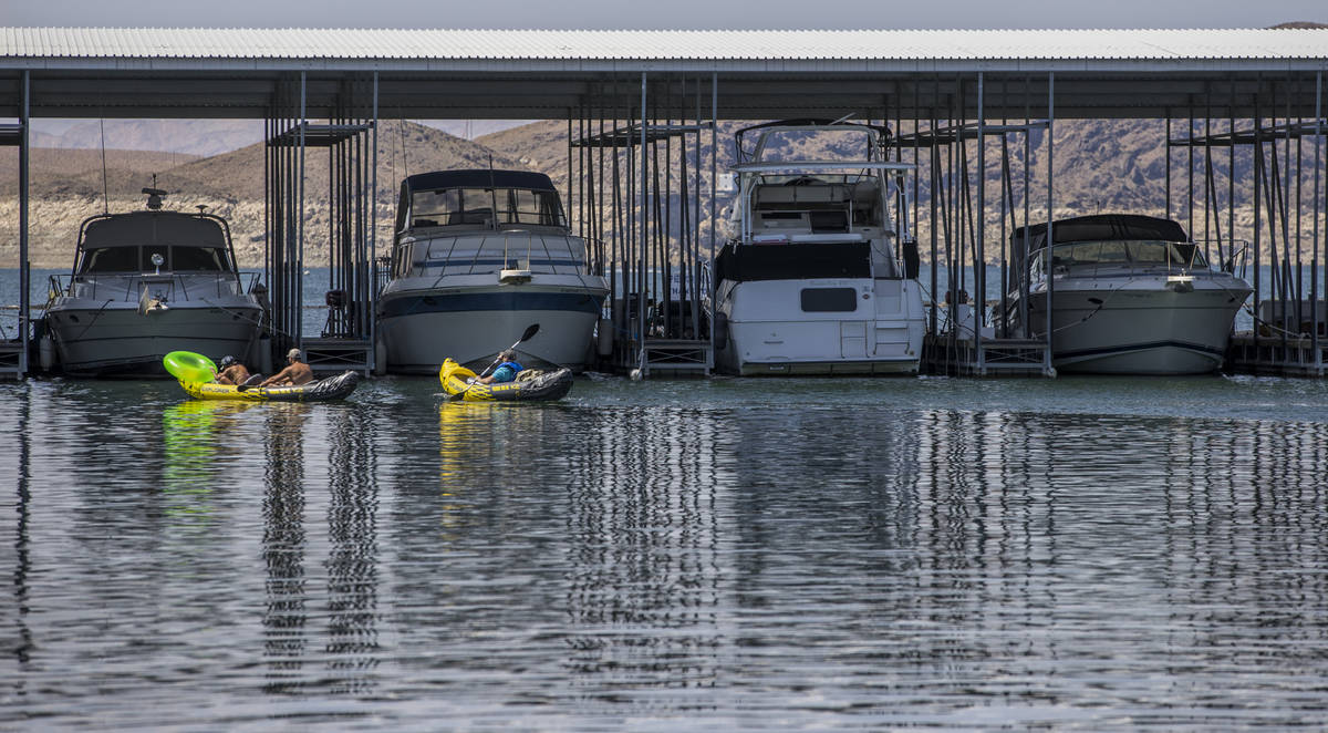 Kayakers move past moored boats at the Las Vegas Boat Harbor in the Lake Mead National Recreati ...