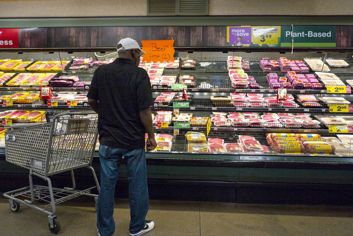 A man looks at beef as a sign indicates a limit of one beef item per shopper in the meat sectio ...