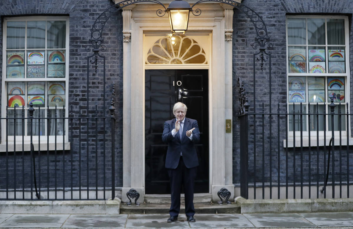 Britain's Prime Minister Boris Johnson applauds on the doorstep of 10 Downing Street in London ...