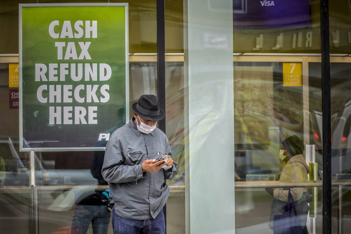 In this April 3, 2020, photo, a man wearing a face mask due to COVID-19 concerns stands outside ...