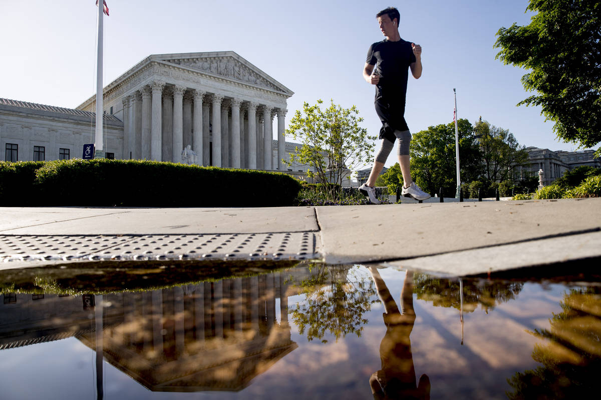 A man runs past the Supreme Court where the justices will hold arguments by telephone for the f ...