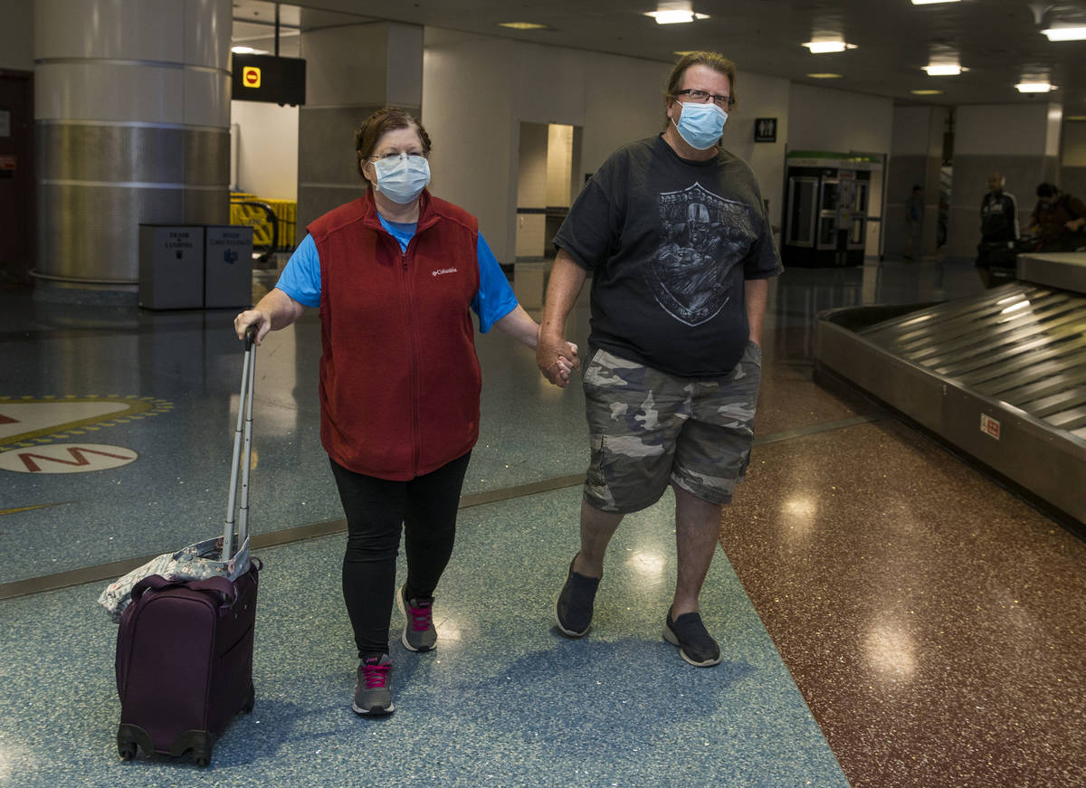 Susan Yowell and husband Jack hold hands as she arrives at the Terminal 1 baggage claim in McCa ...