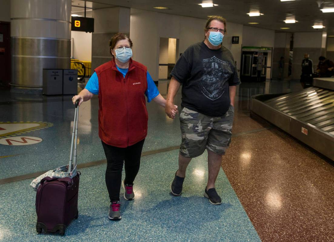 Susan Yowell and husband Jack hold hands as she arrives at the Terminal 1 baggage claim in McCa ...