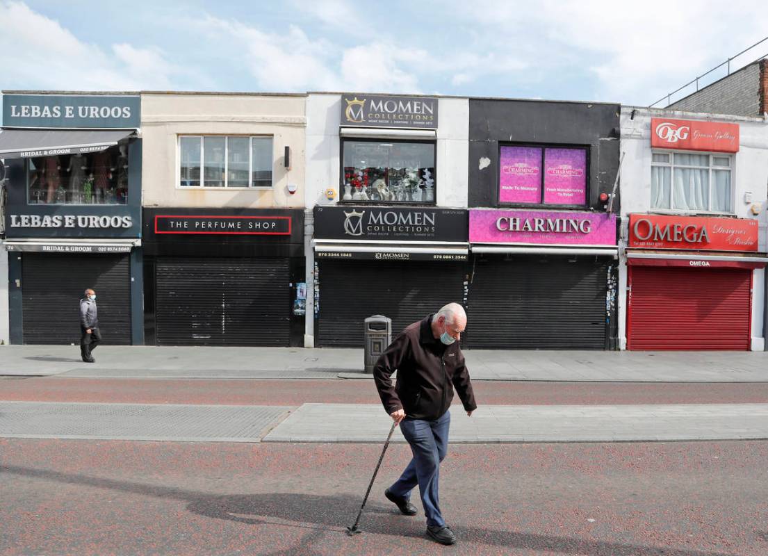 Pedestrians walk along side closed shops during the coronavirus lockdown in London, Tuesday, Ma ...