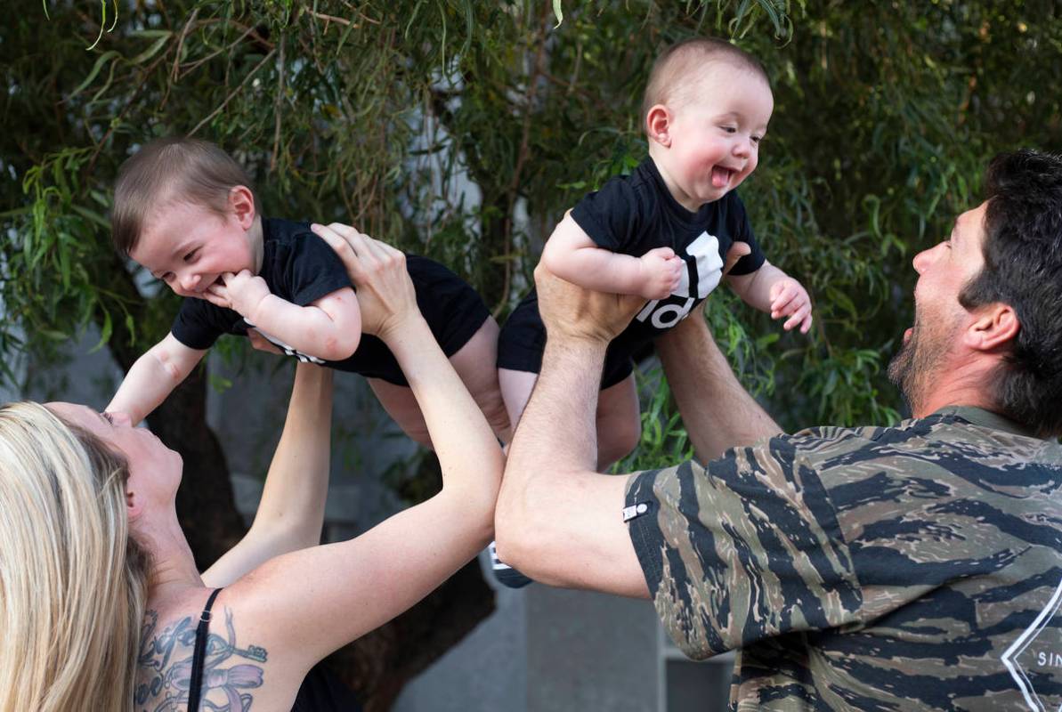 Shannon and David Belford play with their 9-month-old twin sons, Gavin and Garrett, outside the ...