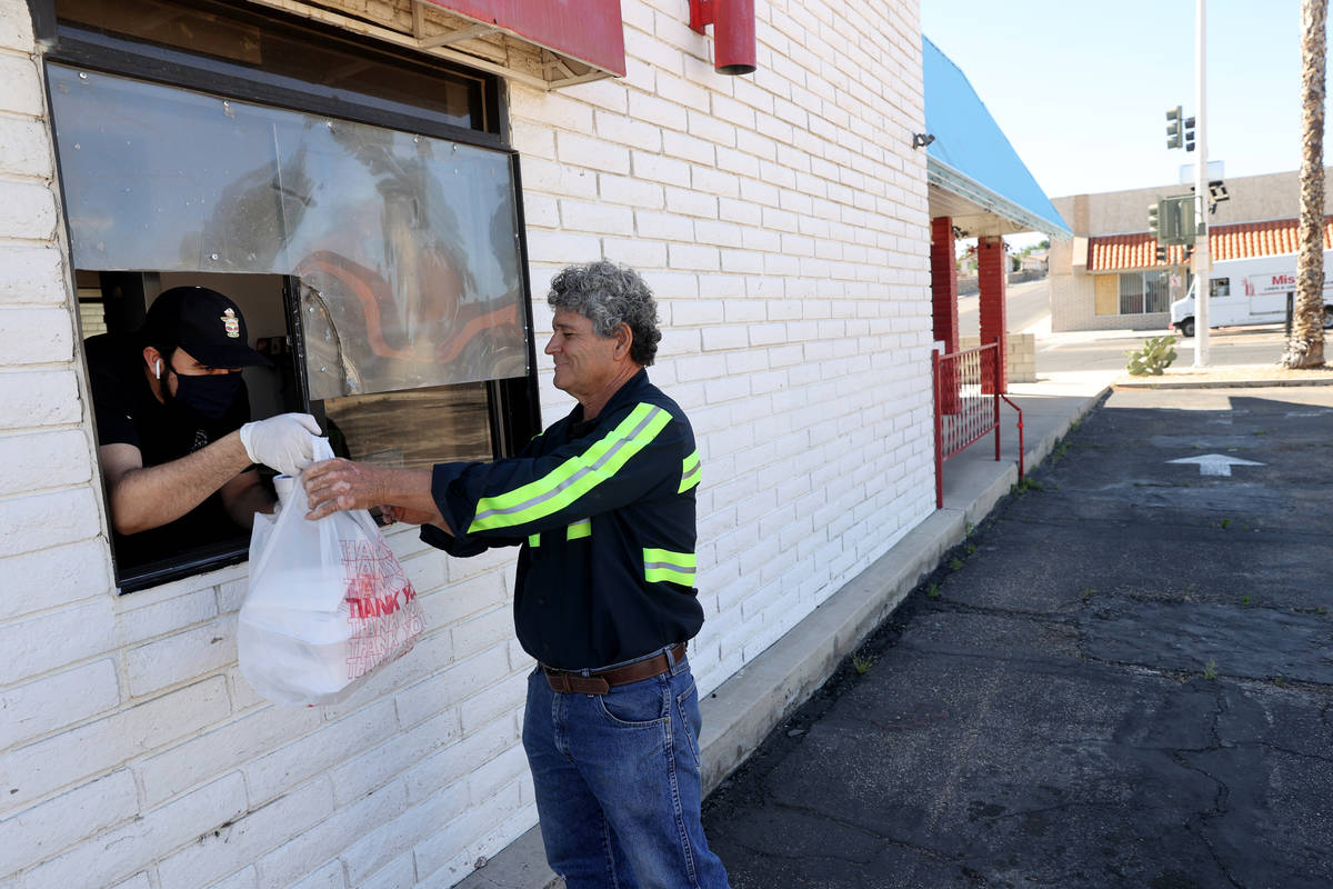 Uvaldo Covian, 30, who owns Roy's Cafe with his family, delivers food to Joel Valenzuela, 65, o ...