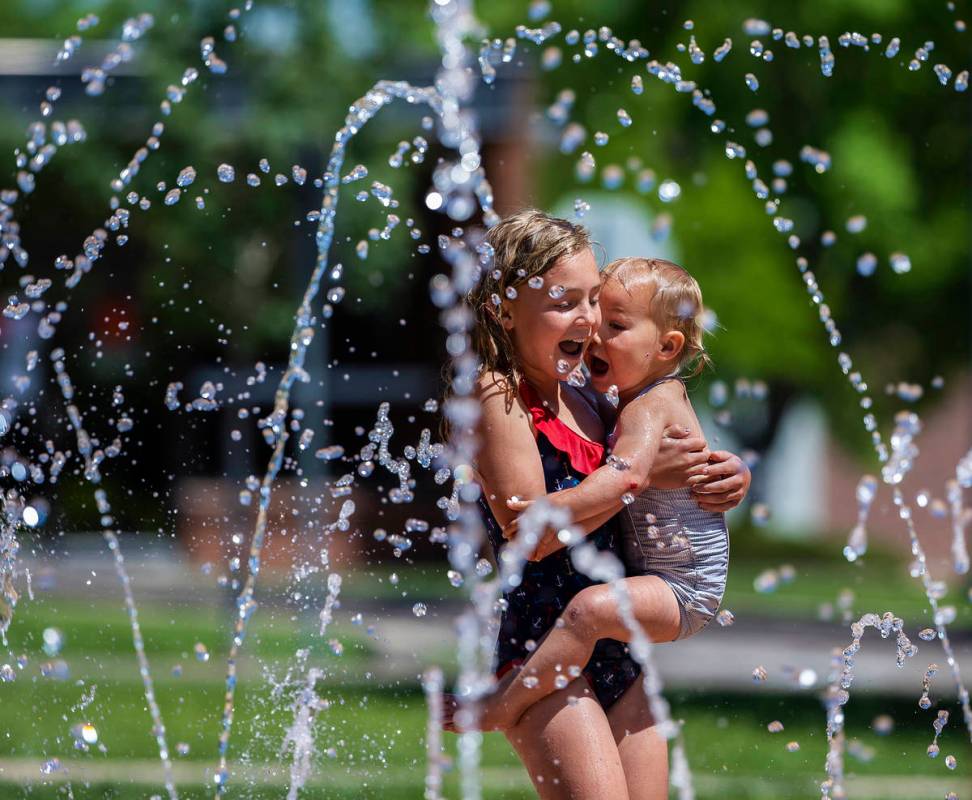 Skye Moyle, left, holds sister Demi, 2, as they play in the fountains at Town Square Park on Tu ...