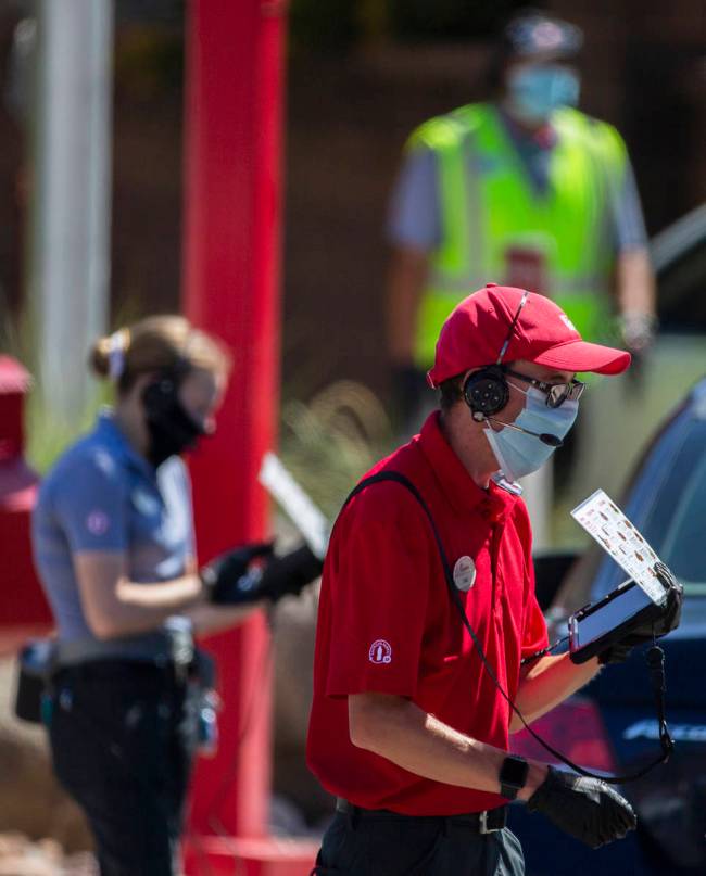 Chick-fil-A employees wearing medical masks take drive through orders on Tuesday, May 5, 2020, ...