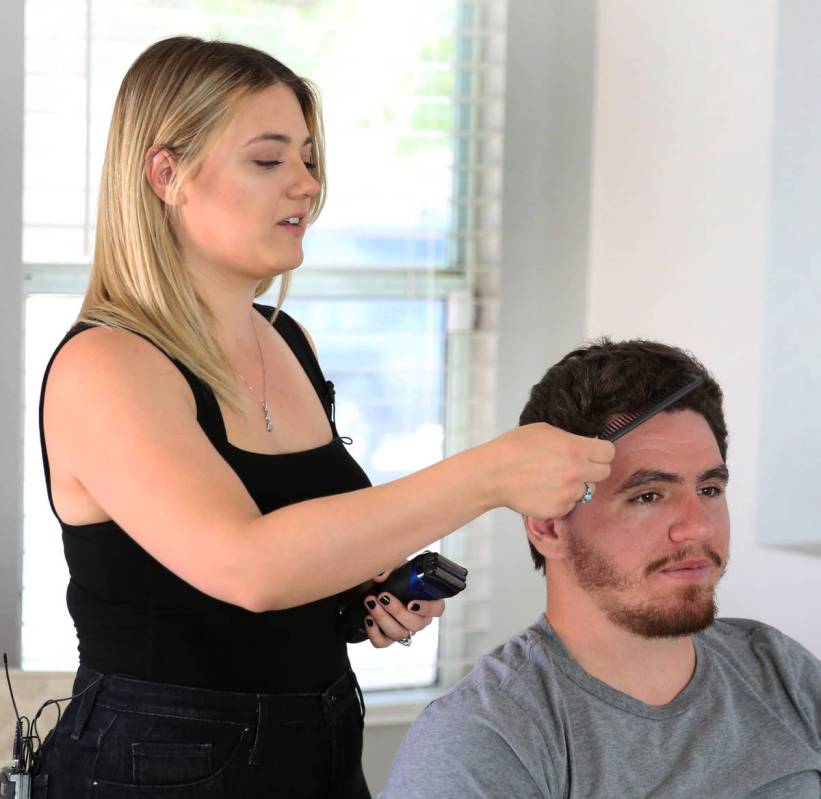 Brittany Seitz, a cosmetologist, combs her husband's, Michael, hair prior to demonstrating how ...