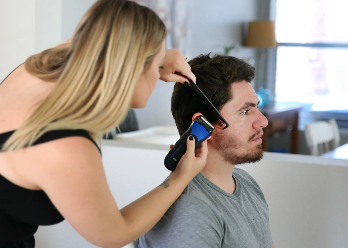 Brittany Seitz, a cosmetologist, cuts her husband's, Michael, hair as she demonstrates how to c ...
