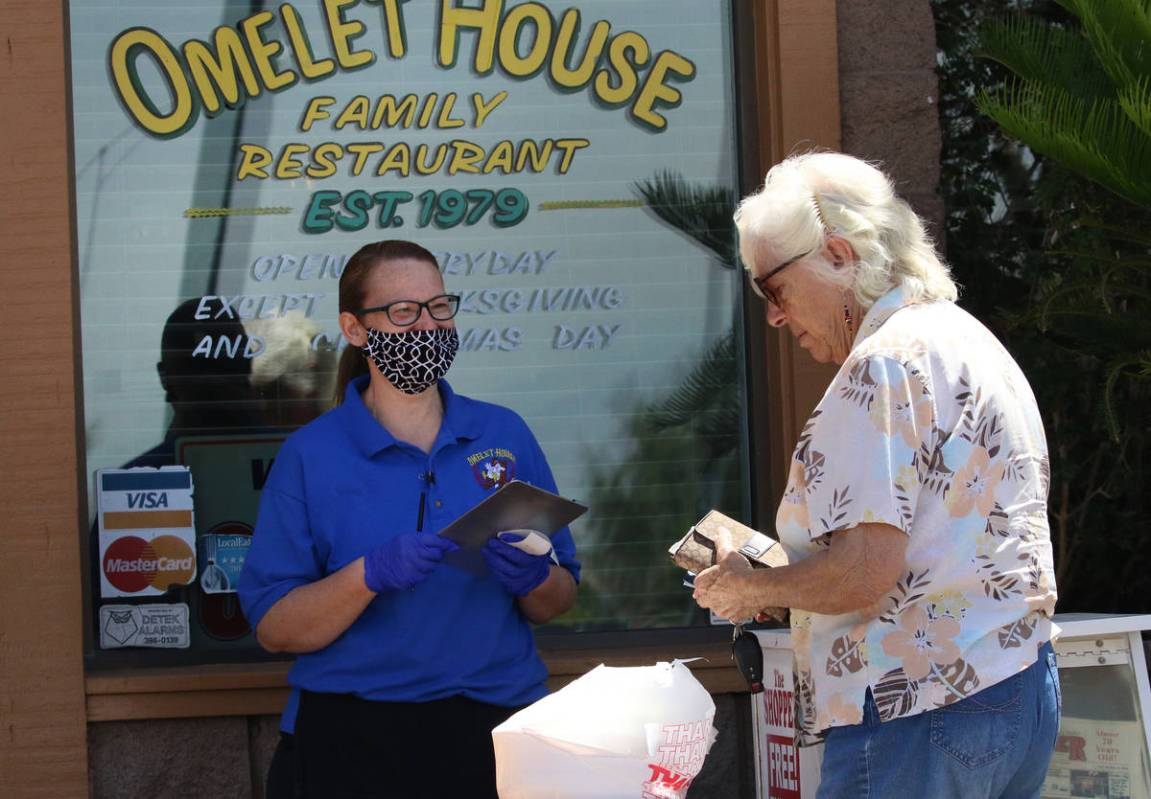 Charlotte Proffitt, right, picks up her order from Pauline Arthur, a waitress, at a curbside pi ...