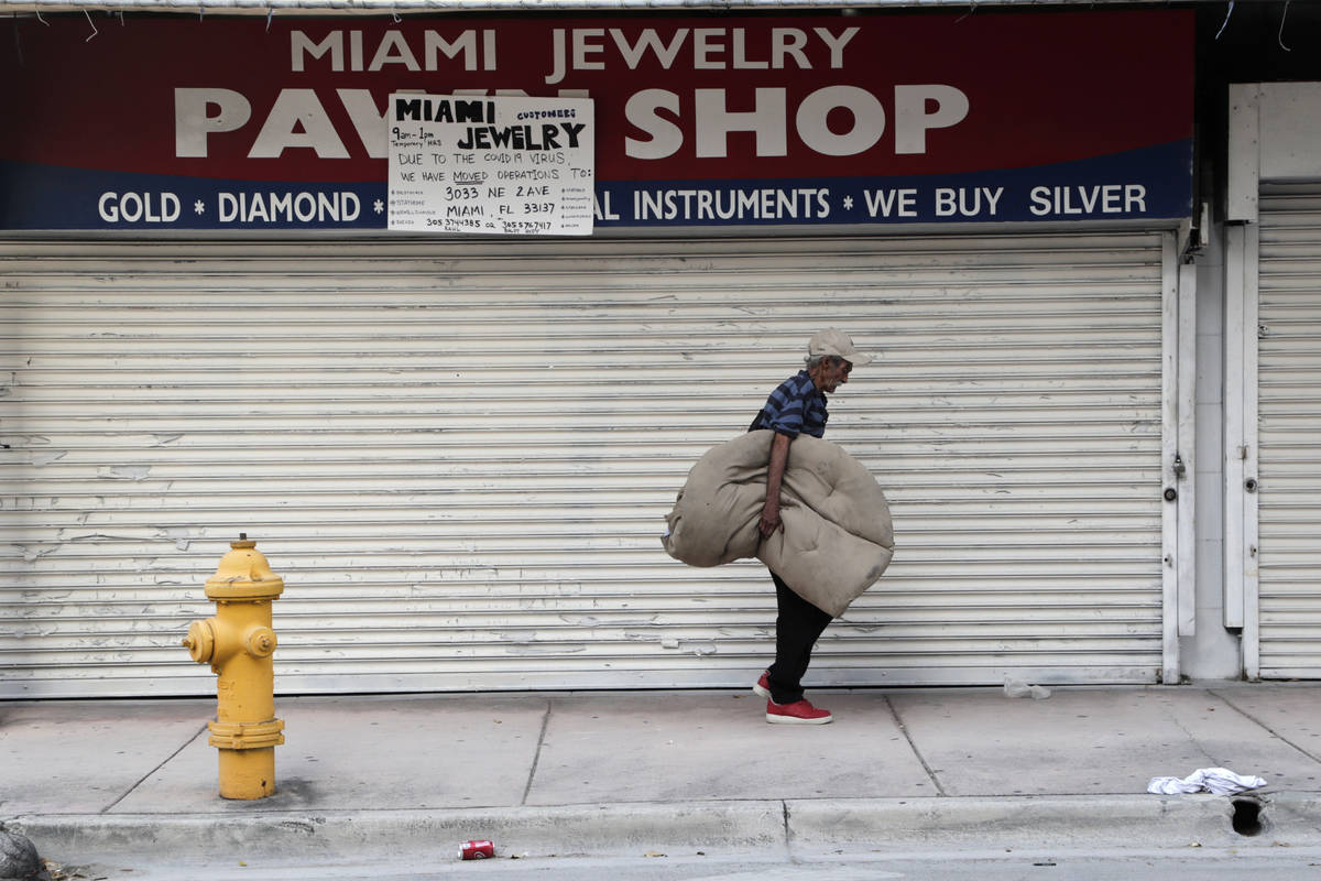 A homeless man carrying his bedding walks past the Miami Jewelry Pawn Shop during the new coron ...