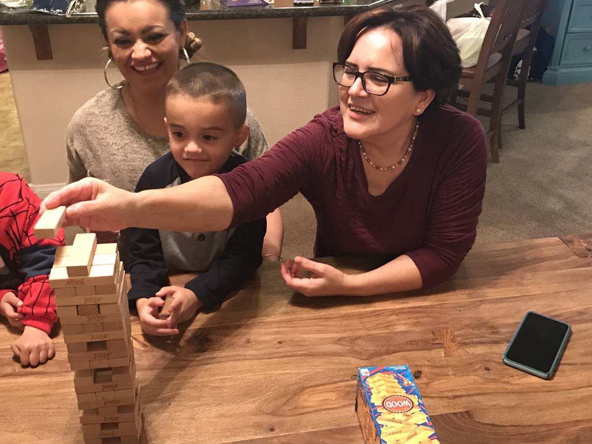 Angelica Rodriguez, 62, plays the game Jenga with one of her 12 grandchildren and her daughter, ...