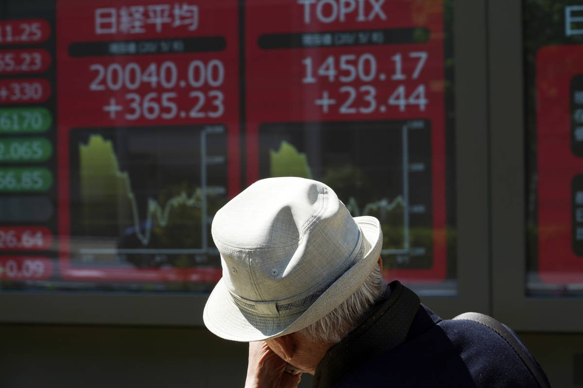 A man walks past an electronic stock board showing Japan's Nikkei 225 index at a securities fir ...