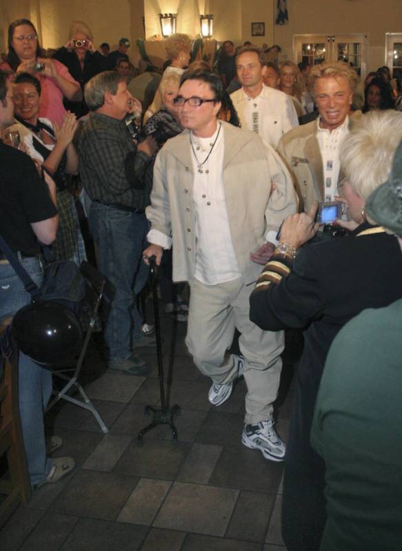 Roy Horn walks with the aid of a cane and a hand from Siegfried Fischbacher in a musical proces ...