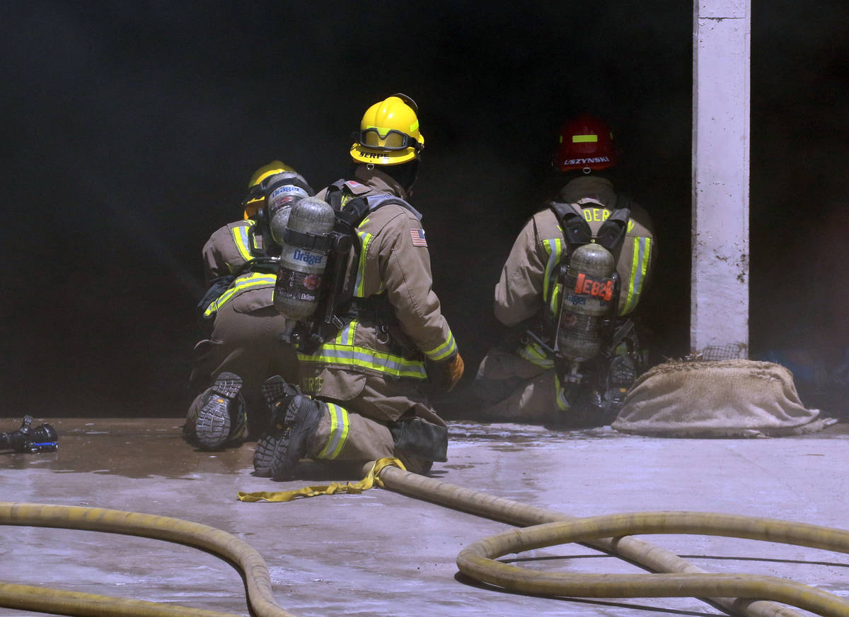 Henderson firefighters battle a fire in a storm drain that generated a large amount of smoke on ...