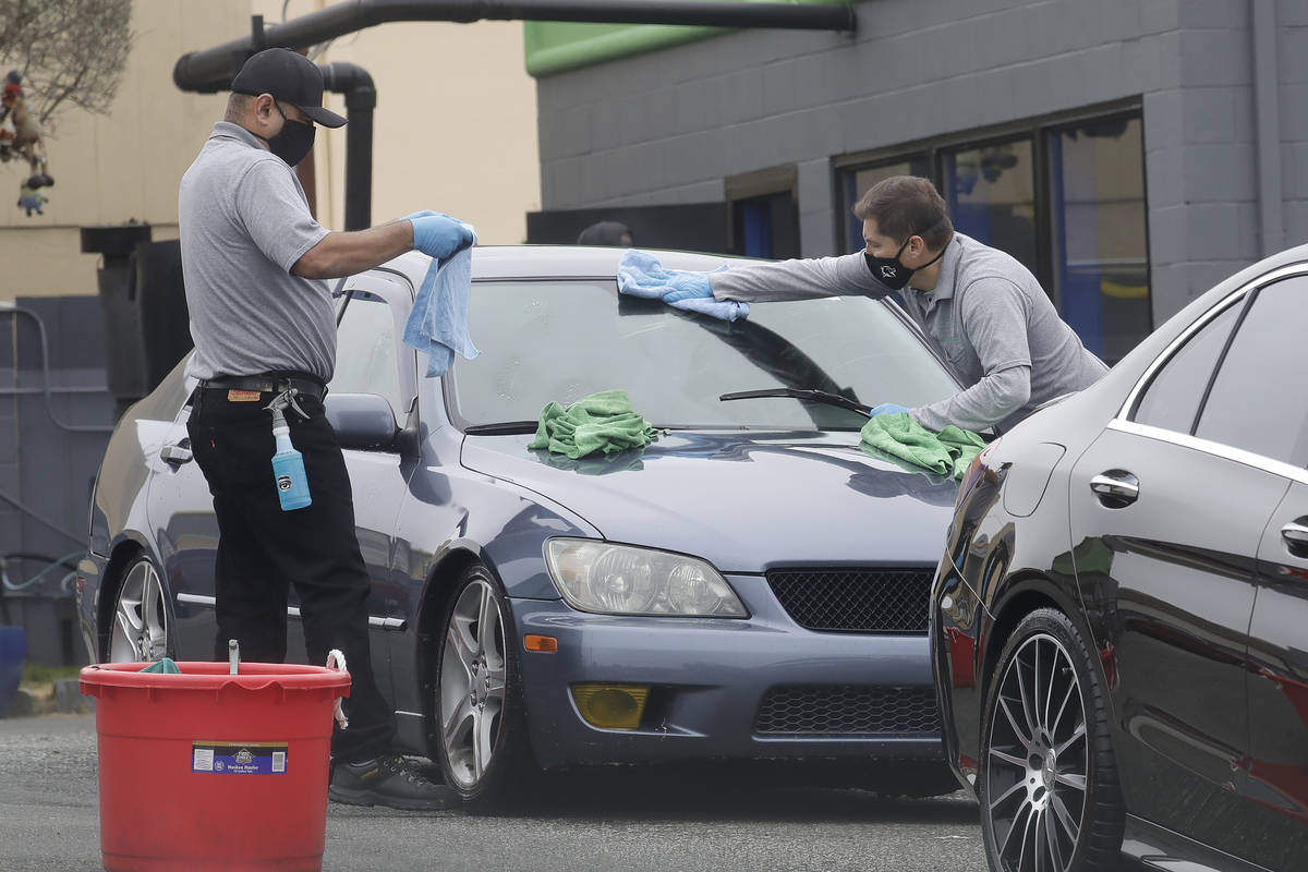 Workers wear face masks while washing cars at Westlake Eco Soft Touch during the coronavirus ou ...