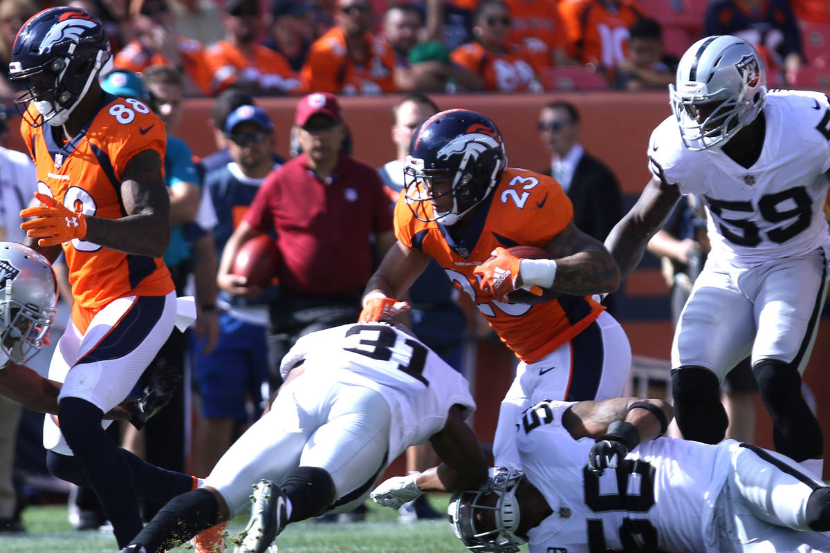 Denver Broncos running back Devontae Booker (23) runs with the football past Oakland Raiders de ...