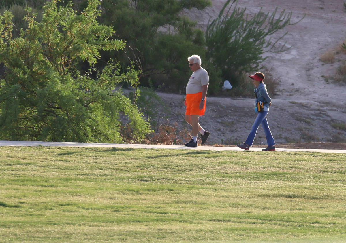 People walk during a cool and windy morning at Charlie Frias Park on Tuesday, May 12, 2020, in ...