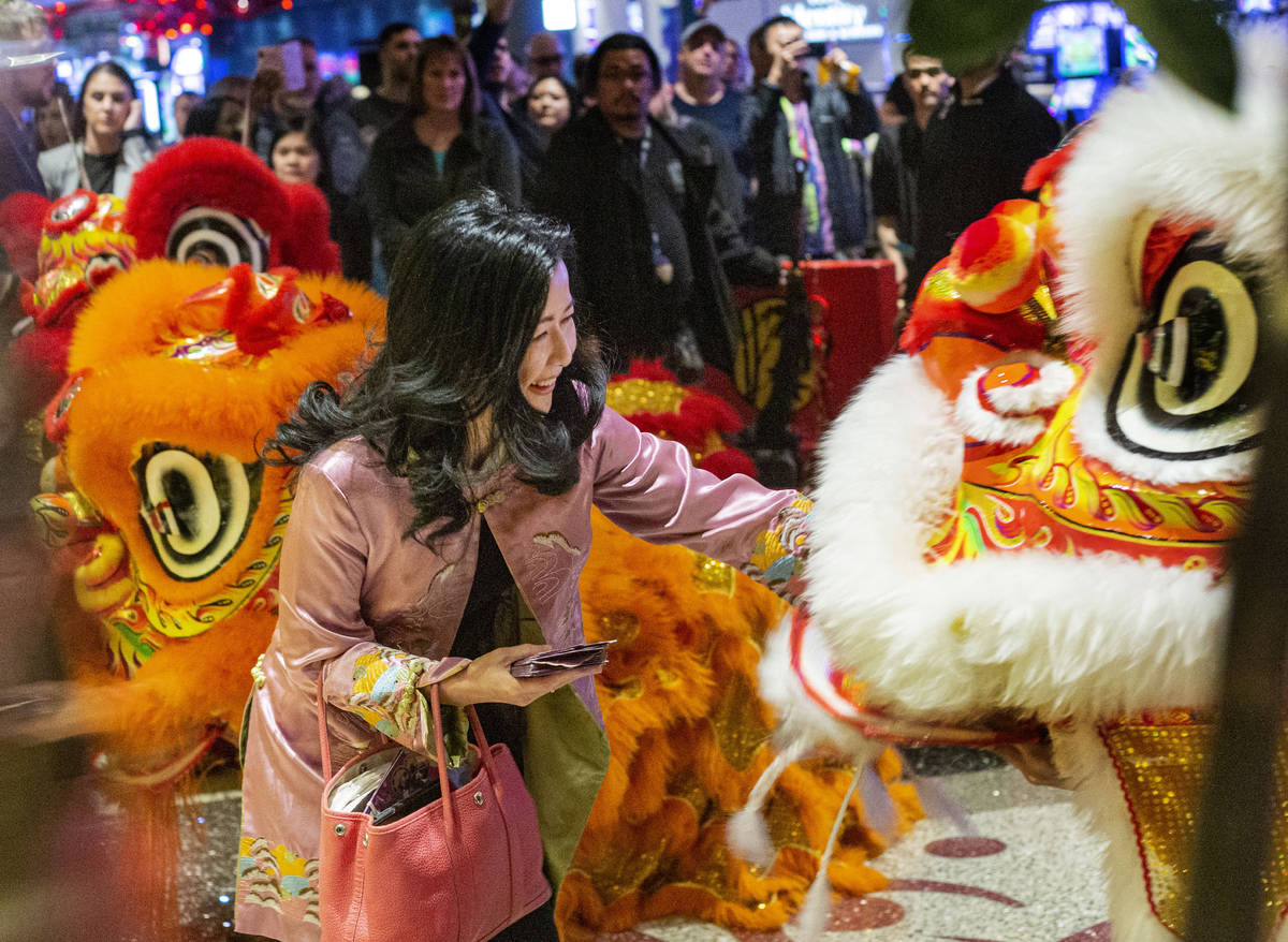 Siew-Lee Yee, president of Far Marketing, feeds a lion during ceremonial dance performance in h ...