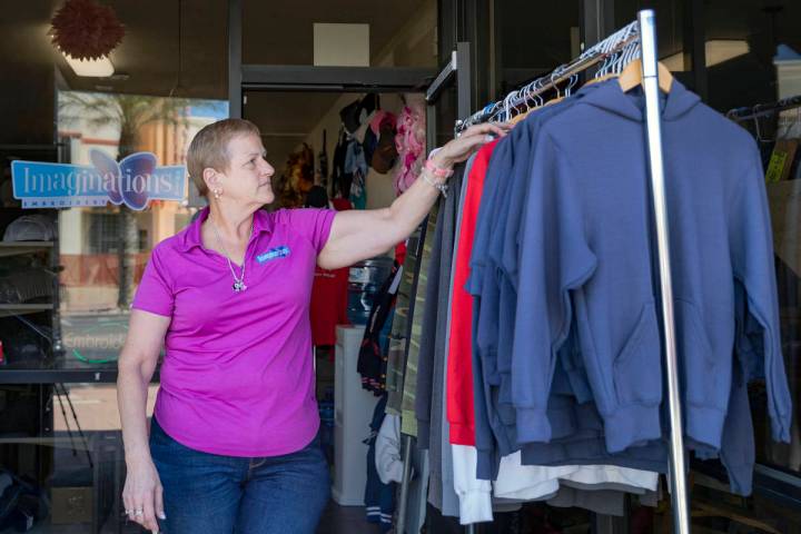 Michele Walker, owner of Imaginations Unlimited, organizes clothes out on the sidewalk to visua ...