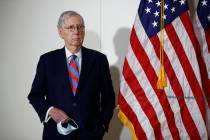 Senate Majority Leader Mitch McConnell of Ky., holds a face mask used to protect against the sp ...