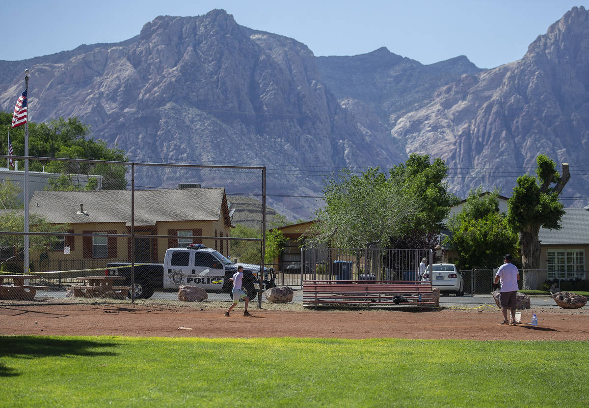 Locals play baseball next to a Las Vegas police vehicle stationed at Blue Diamond Park on Wedne ...