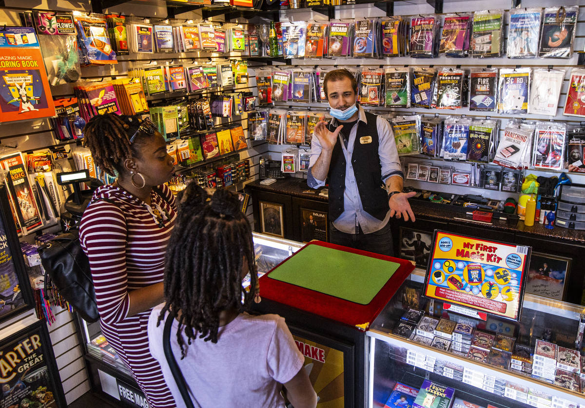 Eric Maynard, store manager at Las Vegas Magic Shop, shows off a magic trick to Naja, left, and ...