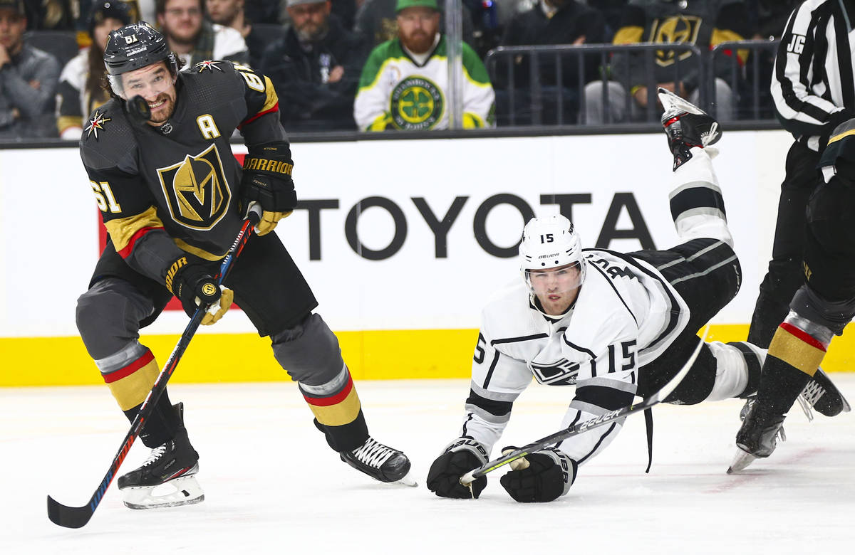 Golden Knights' Mark Stone (61) eyes the puck as Los Angeles Kings' Ben Hutton (15) gets trippe ...