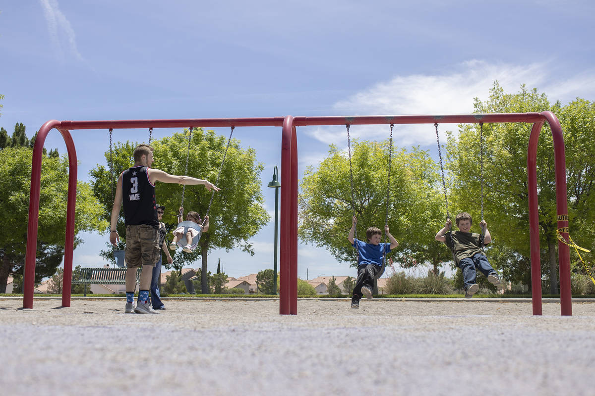 David Cotterell and Mikayla Fitzgerald push 2-year-old Rhiannon Fitzgerald's swing, left, as 8- ...