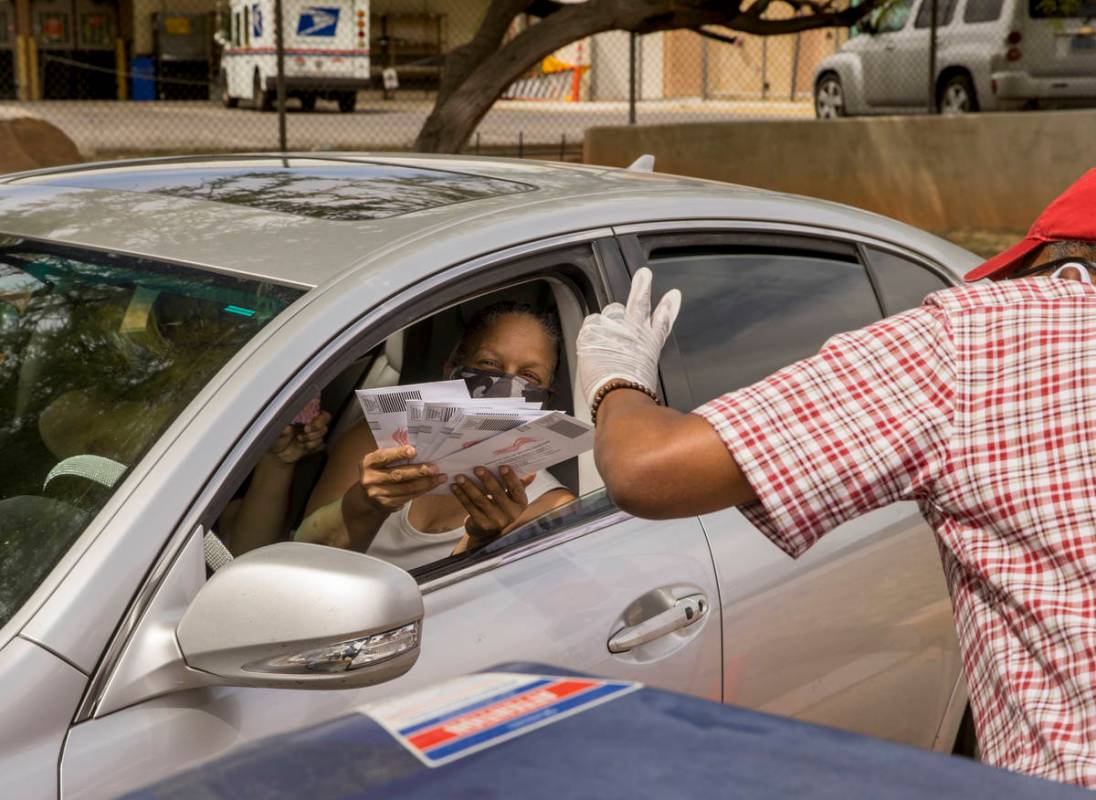 A driver hands over completed ballots to Clark County Commission Vice Chairman Lawrence Weekly ...