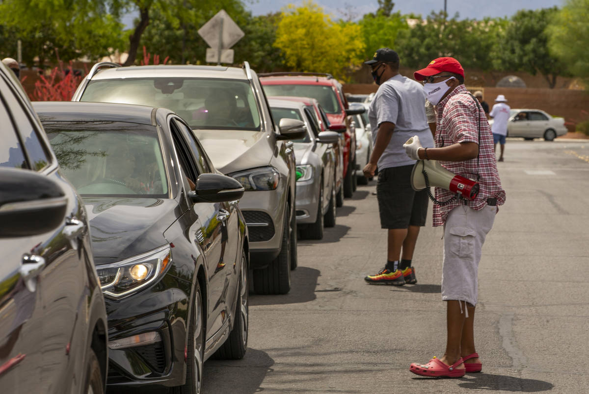 Clark County Commission Vice Chairman Lawrence Weekly chats up drivers waiting in line while du ...