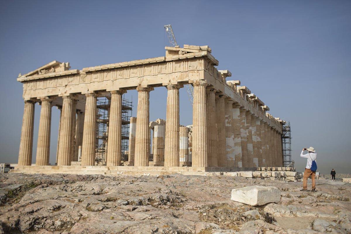 A man takes a picture next the ancient Parthenon temple at the Acropolis hill of Athens, on Mon ...