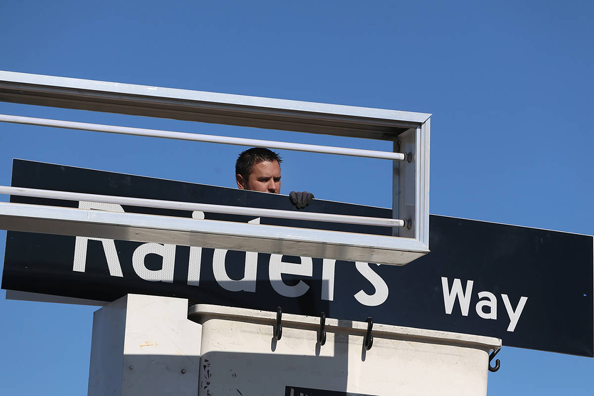 Adam Anderson, a driver traffic signal technician for the city of Henderson, installs a Raiders ...